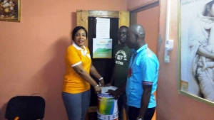 La présidente de l&#039;ONG, Touré Massaty Konet, remet un pot de peinture à Traoré Issouf, conseiller du directeur du COM,